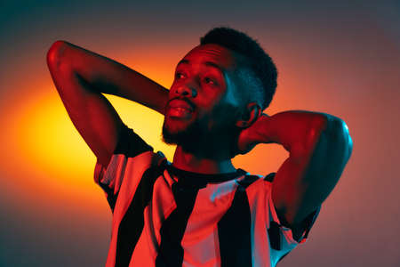 African-american young mans portrait on dark studio background in neon. Concept of human emotions, facial expression, youth, sales, ad.の写真素材