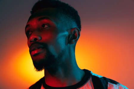 African-american young mans portrait on dark studio background in neon. Concept of human emotions,...