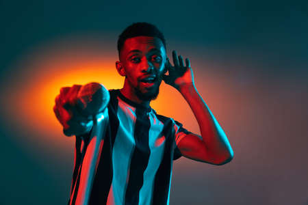 African-american young mans portrait on red studio background in neon. Concept of human emotions, facial expression, youth, sales, ad.の写真素材