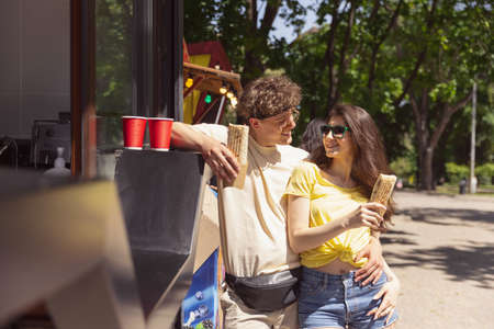 Happy attractive young couple romantically eating a fresh pizza outdoors.の写真素材