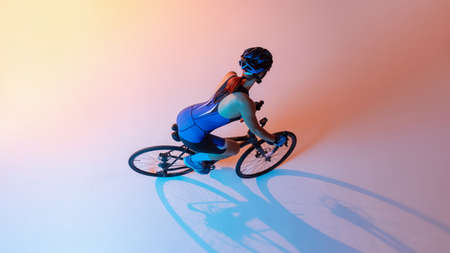 High angle view of female cyclist riding a bicycle isolated against neon backgroundの写真素材