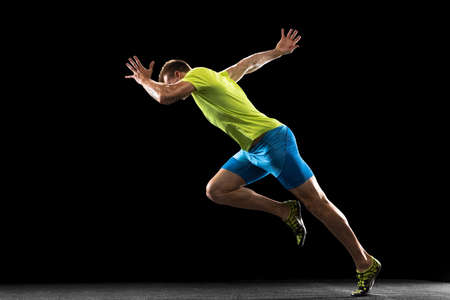 Caucasian professional male athlete, runner training isolated on black studio background. Muscular,...
