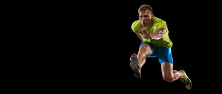 Athlete man athlete jumps over the barrier isolated on black background.