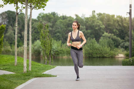 Young female runner, athlete is jogging in the city street in spring sunshine. Beautiful caucasian...