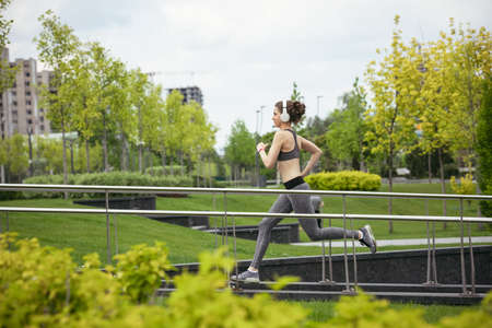 Young female runner, athlete is jogging in the city street in spring sunshine. Beautiful caucasian...