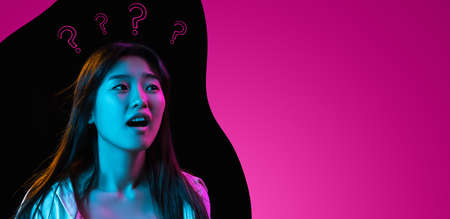 Young beautiful Asian girl isolated over pink black abstract background in neon light. Concept of beauty, fashion,ad. Flyerの写真素材