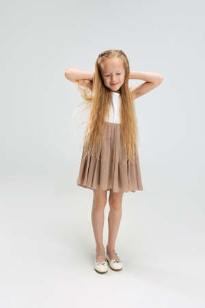 Beautiful little girl in modern stylish dress posing isolated on white studio background. Happy childhood concept.の写真素材