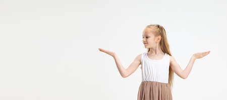 Half length portrait of cute little girl in modern stylish dress posing isolated on white studio background. Happy childhood concept.の写真素材