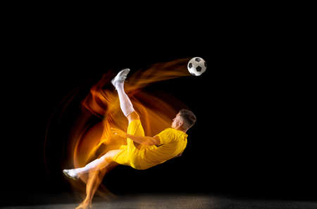 One caucasian male football or soccer player training with ball in mixed light isolated on dark background. Concept of professional sport, active, motion..の写真素材