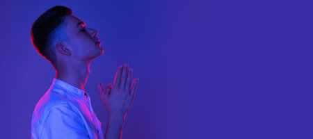 Flyer. One Caucasian young man posing isolated on blue studio background in neon pink light. Concept of human emotions, facial expression.の写真素材