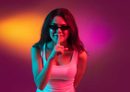 Caucasian young womans portrait on dark studio background in neon. Concept of human emotions, facial expression.の写真素材