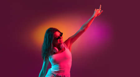 Caucasian young womans portrait on dark studio background in neon. Concept of human emotions, facial...