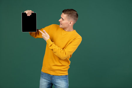 Portrait of young Caucasian man posing isolated over green studio background with copyspace for ad. Concept of human emotionsの写真素材