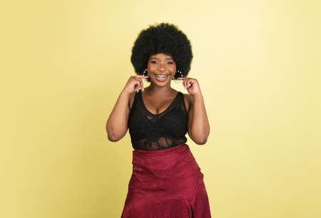 Portrait of African young woman isolated over light yellow studio background. Concept of human emotions, facial expression, youth, sales, ad.の写真素材