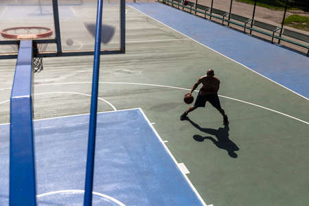One african-american male basketball player training at street public stadium, sport court or palyground outdoors. Concept of healthy active lifestyle, motion, hobby.の写真素材