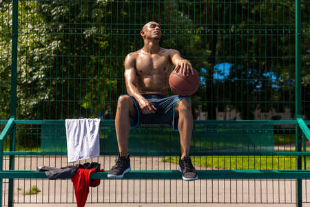 Young strong man, male basketball player practicing at street public stadium, sport court or palyground outdoors. Concept of healthy active lifestyle, motion, hobby.の写真素材