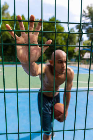 Workout. Young strong man, male basketball player training at street public stadium, sport court or palyground outdoors. Concept of healthy active lifestyle, motion, hobby.の写真素材
