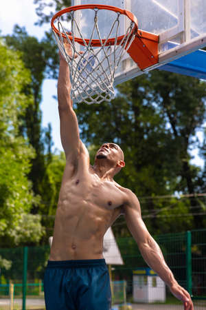 Workout. Young strong man, male basketball player training at street public stadium, sport court or...