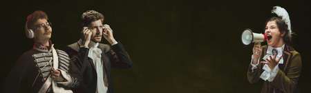 Medieval people as a royalty persons in vintage clothing on dark background. Concept of comparison of eras, modernity and renaissance, baroque style.の写真素材