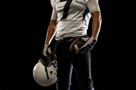 Cropped image of male American football player, athlete posing isolated on black studio background. Concept of professional sport, championship, competition.の写真素材