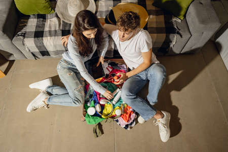 Young happy married couple having fun, preparing for summer vacation sitting at home, indoors. Taking right decision. Look excited, delighted.の写真素材