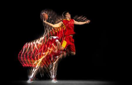Flight. Young caucasian basketball player in motion and action isolated on dark background with stroboscope effect. Concept of professional sport, hobby.の写真素材