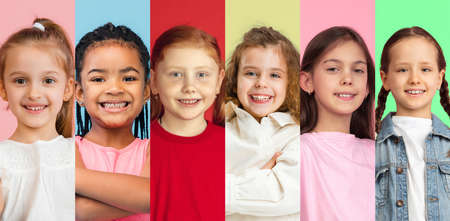 Close-up portraits of little cute smiling kids, girls isolated on multicolored studio background....