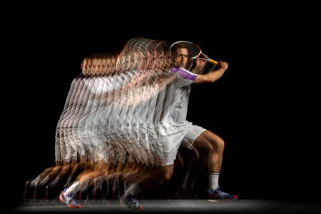 Power and speed. Young man, professional tennis player in motion and action isolated on dark background with stroboscope effect.の写真素材