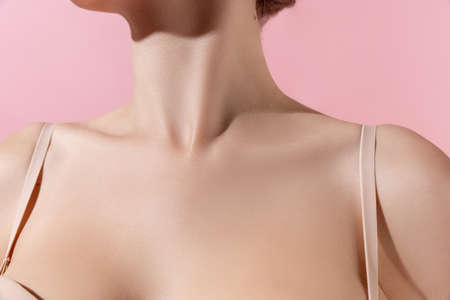 Close up female neck, collarbones isolated on pink studio background. Beautiful caucasian woman with well-kept skin.の写真素材