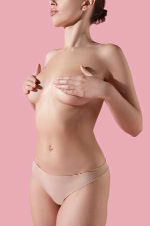 Portrait of young slim naked woman isolated over pink studio background. Beauty, fitness, diet, sports, plastic surgery and aesthetic cosmetology concept.の写真素材