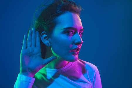 Caucasian womans portrait isolated on blue studio background in pink-green neon light, stylish and beautifulの写真素材