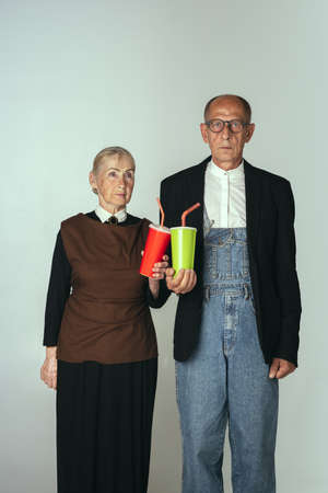 Elderly man and woman in art performance, replica of painting american gothic. Retro style, comparison of eras and cultural, humor concept.の写真素材