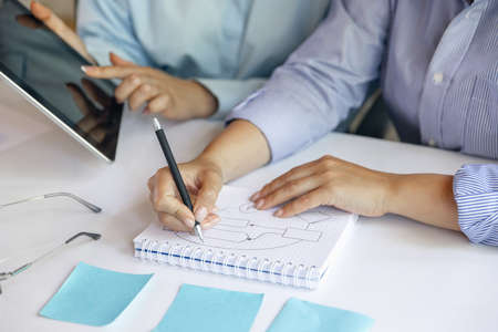 Two young women, colleguas during working day, business meeting. Using laptop, modern gadgets,...