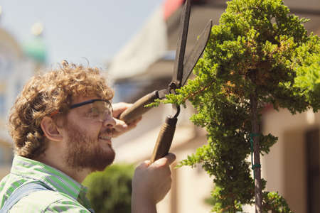 Portrait of redheaded bearded man, farmer with big garden scissors prining trees in garden, outdoors Concept of professional occupation, work.の写真素材