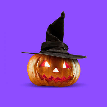 Scary Halloween pumpkin under black witch hat isolated on purple background, the night of fear.の写真素材