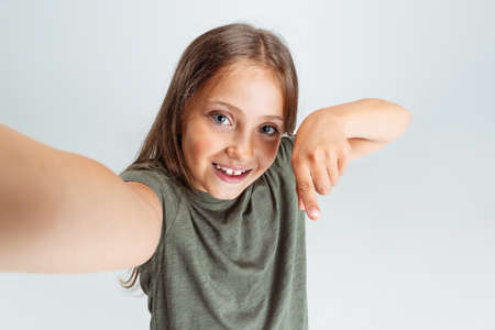 Close-up portrait of beautiful preschool smiling girl looking at camera isolated on white studio background. Copyspace for ad. Childhood, education, emotion conceptの写真素材