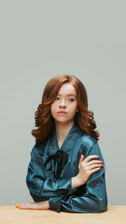 Portrait of young redheaded girl in retro style, fashion of 70s, 80s years isolated on gray studio...