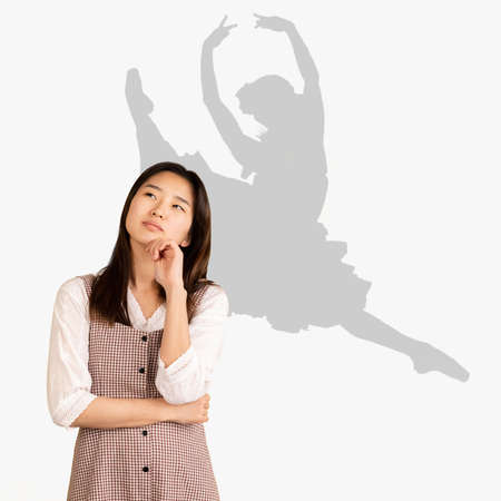 Young asian girl dreaming about future career. Becoming a famous ballerina. Shadow of dreams on the...