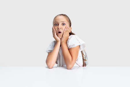 Close-up beautiful Caucasian preschool girl looking at camera isolated over white studio background....