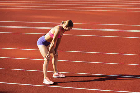 One Caucasian woman, female athlete, runner training at public stadium, sport court or palyground...