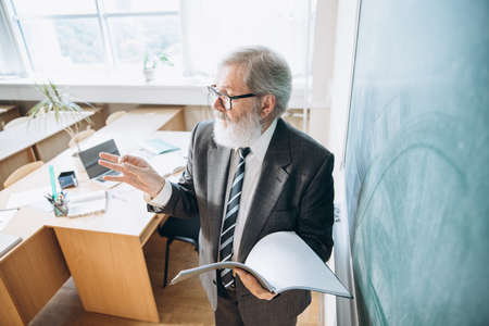 High angle view of elderly gray-headed man, professor, teacher at lecture, lesson at classroom,...