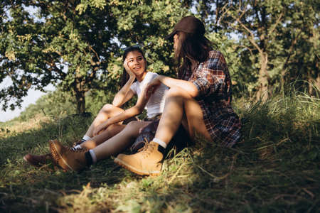 Young girls, friends walking, strolling together outskirts of city, at summer forest. Active...