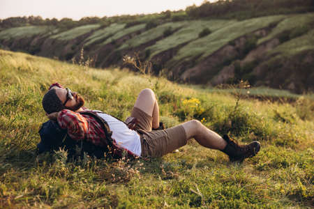 Close-up young man walking, strolling alone outskirts of city. Beautiful landscape views. Active lifestyle, travel conceptの写真素材