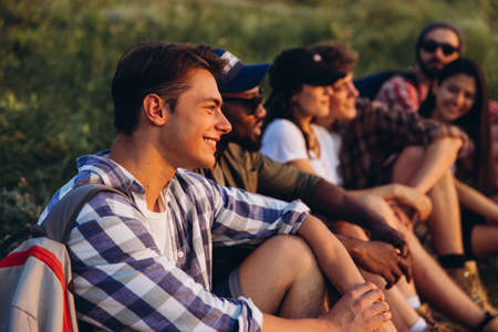 Meet sunset. Group of friends, young men and women walking, strolling together during picnic in summer forest, meadow. Lifestyle, friendship,の写真素材