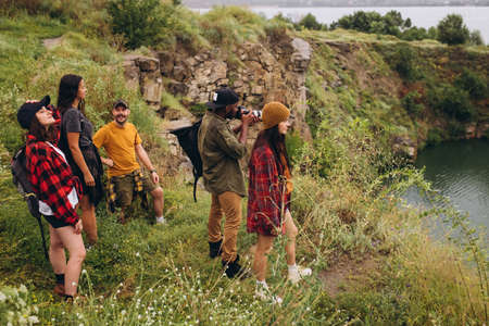 Group of friends, young men and women walking, strolling together outskirts of city, in summer...