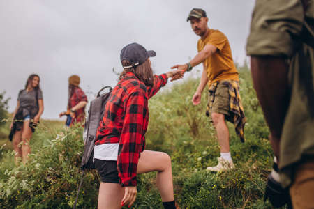 Support, love. Group of friends, young men and women walking, strolling together outskirts of city, in summer forest, meadow. Active lifestyle, friendship, care, ecology conceptの写真素材