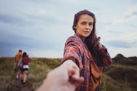 Come with me. Beautiful girl holding man by hand and walking down the mountain valley looks and...