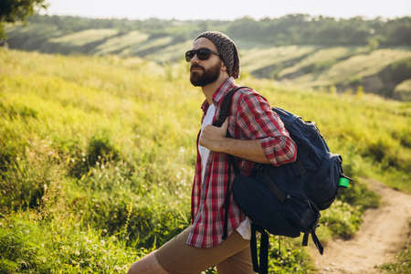 In summer in nature. Close-up young man walking, strolling alone outskirts of city. Beautiful landscape views. Active lifestyle, travel conceptの写真素材