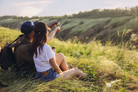 Close-up young man and woman, family couple sitting together in meadow, field and enjoy nature....