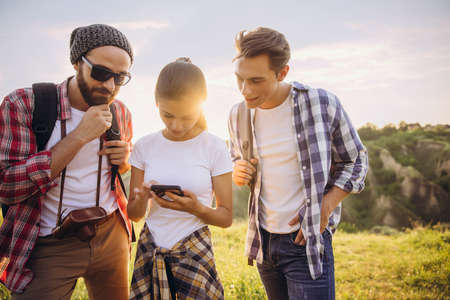 Group of friends, young men and woman walking, strolling together in summer forest, meadow. Active lifestyle, friendship, travel conceptの写真素材